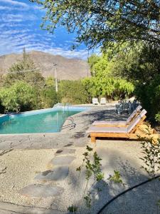 a swimming pool with a wooden bench next to it at Casa rural en el Valle de Elqui in Vicuña
