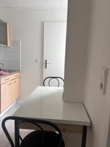 a white kitchen with a table and a black chair at Apartment Hameln Klein Berkel in Hameln