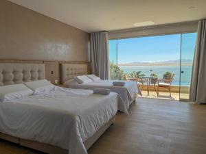 two beds in a bedroom with a view of the ocean at Hotel El Condor in Paracas