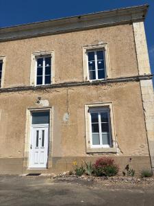 a building with two windows and a white door at Les Paddocks du Damier Manceau in Marigné-Laillé