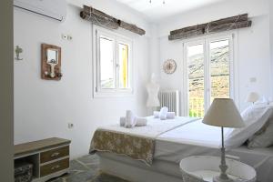 a white bedroom with a bed and a window at Terramare Villa's 4 in Kithnos