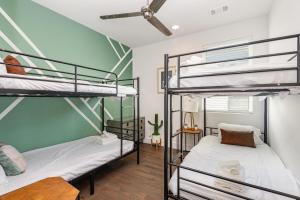 two bunk beds in a room with a green wall at Double Time - Ping-Pong Table - Mins to Germantown in Nashville