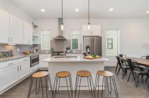 a kitchen with white cabinets and a island with bar stools at Double Time - Ping-Pong Table - Mins to Germantown in Nashville
