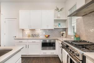 a white kitchen with white cabinets and a stove at Double Time - Ping-Pong Table - Mins to Germantown in Nashville