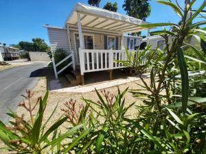 瓦尔拉普拉日Mobil Home CAMPING LES SABLES DU MIDI的一座带门廊和白色围栏的小房子