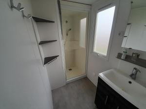瓦尔拉普拉日Mobil Home CAMPING LES SABLES DU MIDI的带水槽和淋浴的白色浴室