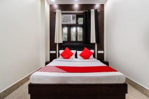 a bedroom with a large bed with red pillows at Hotel O Chandra in Lucknow