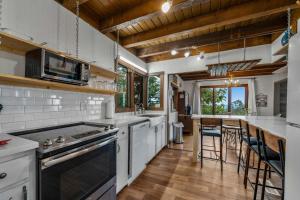 a kitchen with white cabinets and a stove top oven at Mountain Retreat Ruby's Roost Home & Loft in Mentone