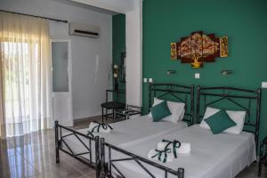 アギオス・ゲオルギオスにあるMirsini Apartmentsの緑の壁のベッドルーム1室(ベッド2台付)