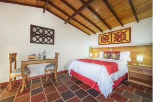 a bedroom with a bed and a table and a desk at Hotel Zocalo Campestre in Guatapé