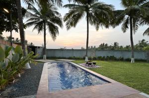 a swimming pool in a yard with palm trees at Rustic Nestle, Tirupur in Tiruppūr