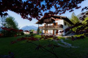 a large house with a balcony in a yard at Pension Waldklause in Schönau am Königssee
