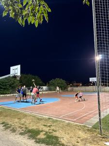 Un grupo de personas jugando baloncesto en una cancha por la noche. en Prince & Princess Apartment Nin, en Nona