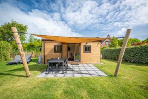 a shed with a table and chairs in a yard at Lodges De Driesprong Domburg in Domburg