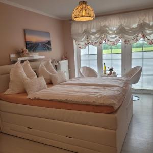 a large bed in a bedroom with a chandelier at Strandmuschel in Aventoft