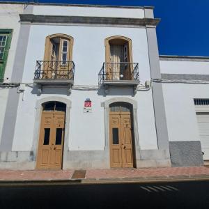 ein weißes Gebäude mit braunen Türen und zwei Balkonen in der Unterkunft El Cachorro in San Miguel de Abona