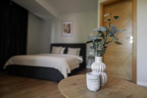 a vase with flowers sitting on a table in a bedroom at Stari Hrast Apartmani in Bosanska Gradiška