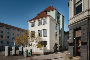 a white building with a brown roof on a street at Sentral leilighet i Bergen in Bergen