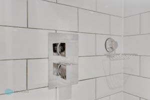 a white tiled bathroom with a shower with a thermos at Bantham Mews by Pureserviced 1 bedroom luxury mews in Plymouth