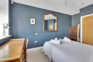 a blue bedroom with a bed and a mirror at Bantham Mews by Pureserviced 1 bedroom luxury mews in Plymouth