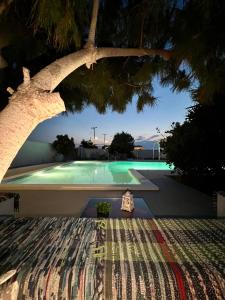 a swimming pool with a tree in the foreground at Santo Margarita in Oia +36 photos