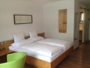 a bed in a room with a green chair at Seehotel Lilly in Strobl