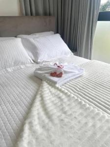 a white bed with a white towel with a ribbon on it at Loft Bamberg 202-Pomerode in Pomerode