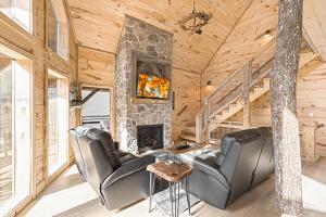 un salon avec deux fauteuils en cuir et une cheminée en pierre dans l'établissement Aspen Lodge by Venture Smoky Mountains, à Gatlinburg