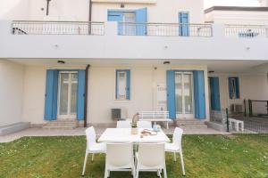 a patio with a white table and white chairs at ANIMA JESOLO - DRAGO VILLAGE, Beach & Pool, 2 Parkings in Lido di Jesolo