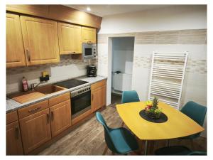 a kitchen with wooden cabinets and a table and chairs at Apartmán Doubrava in Puclice