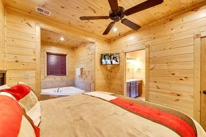Schlafzimmer mit einem Bett, einer Badewanne und einem Deckenventilator in der Unterkunft Bears Den by Venture Smoky Mountains in Gatlinburg