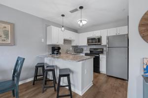 eine Küche mit weißen Schränken und einer Theke mit Stühlen in der Unterkunft Grand Caribbean East Poolside Palms in Pensacola