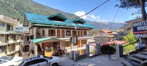 un edificio con techo azul en una calle en Hotel Alfa Manali, en Manali