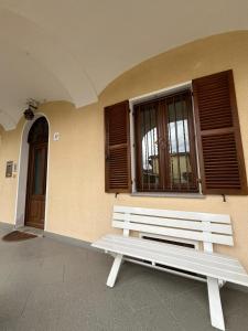 een witte bank naast een gebouw met ramen bij La petite maison Soleil in Biella