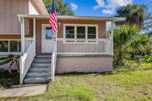 una casa rosa con una bandera americana en el porche en Near Downtown Beach House&Apt - Woodland Escape, en Pensacola