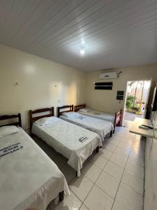 Habitación con 3 camas y ventana. en Hotel Maceió 3 irmãos, en Juazeiro do Norte