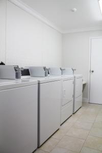 a kitchen with white cabinets and white appliances at Hotel North in North Sydney