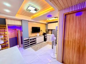 a room with a kitchen with a refrigerator and a tv at Baguio Transient Across Burnham Park 3 - 3BR Condo in Baguio
