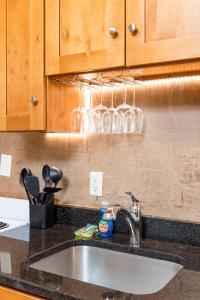 un fregadero con copas de vino colgando encima. en 1BR in the Heart of Downtown Boston Famous Nightlife Theater District with Bed Full of Promises TD Garden Common Park MBTA, en Boston