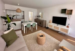 ein Wohnzimmer mit Fernseher und Tisch mit Stühlen in der Unterkunft Vilamoura Living 106 in Quarteira