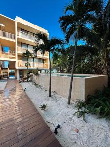 a resort building with palm trees and a boardwalk at Sunset 2BR Apartment Steps from the Beach with Ocean View in Holbox Island
