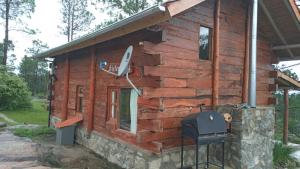 a log cabin with a grill on the side of it at Cabañas Aldea Lucerna La Cumbrecita in La Cumbrecita
