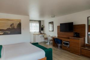 a bedroom with a bed and a desk with a television at Ucluelet Wildwood Inn in Ucluelet