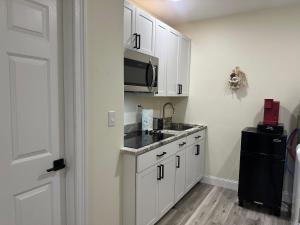 a kitchen with white cabinets and a sink and a microwave at Magic Secluded Suite-Pool-Sauna plus Lake View Venice Florida in Venice +11 photos