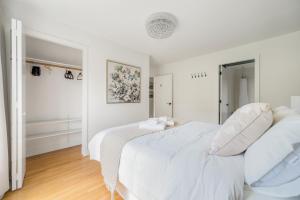 a white bedroom with a large bed with white pillows at Comfort House in Kerrisdale Private and Shared Rooms in Vancouver