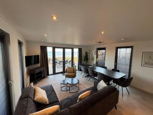 a living room with a couch and a table at Enkhuizer Strand BeachHouse Panoramadeck mit Zaun Nr 415 in Enkhuizen
