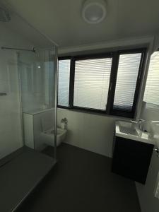 a bathroom with a shower and a toilet and a sink at Enkhuizer Strand BeachHouse Panoramadeck mit Zaun Nr 415 in Enkhuizen +14 photos