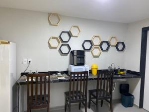 a kitchen with a counter with chairs and a microwave at Hostel Vila Suites in Vila Velha