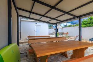 a patio with wooden benches and a table at Apartments Mirela in Karlobag +33 photos