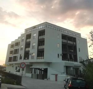 un grand bâtiment blanc avec des voitures garées devant dans l'établissement Apartman Vuk, à Bar 2 autres photos